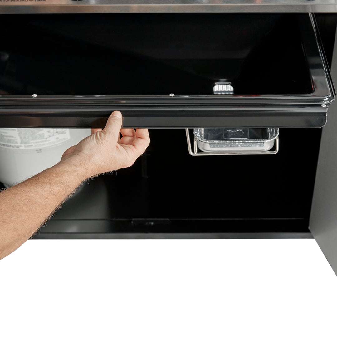 a hand pulling a grease trap on a Weber Genesis barbecue